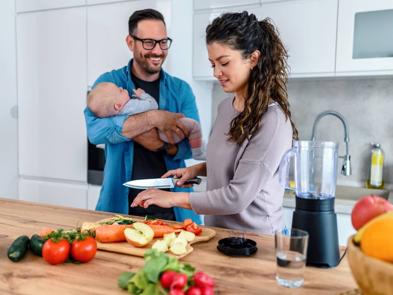 Mladá rodina pripravuje zdravú večeru v kuchyni a debatujú na tému životného poistenia.