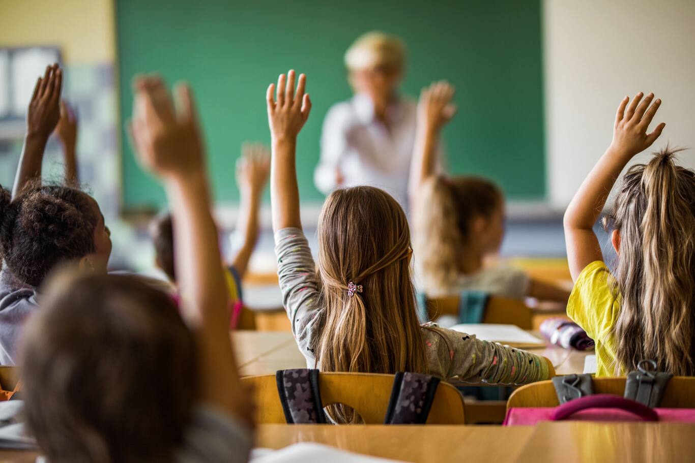 deti sedia v školskej triede a hlásia sa