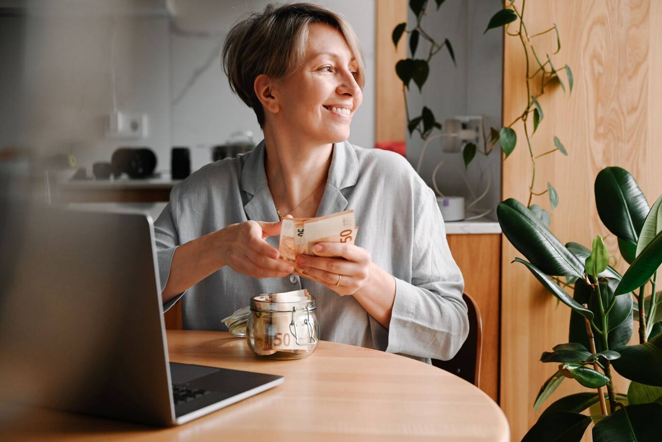 Žena, ktorá počíta peniaze, drží 50-eurové bankovky v ruke a sedí v kuchyni