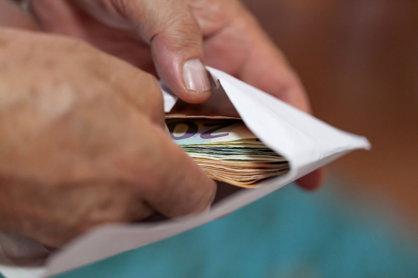 Finančné prostriedky pripravené na výplatu z obálky symbolizujú čerpanie úspor na dôchodok.