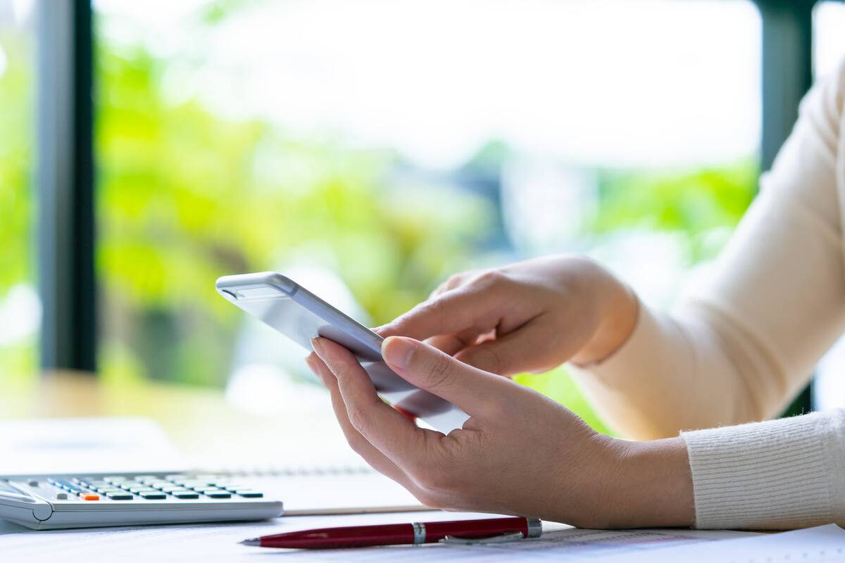 Mladá žena na mobile v jej dome pri veľkom presvetlenom okne