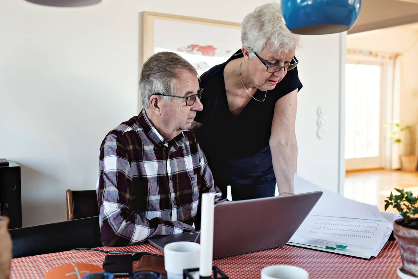 Starší manželský pár za stolom počítajúci mesačné výdavky a rozpočet