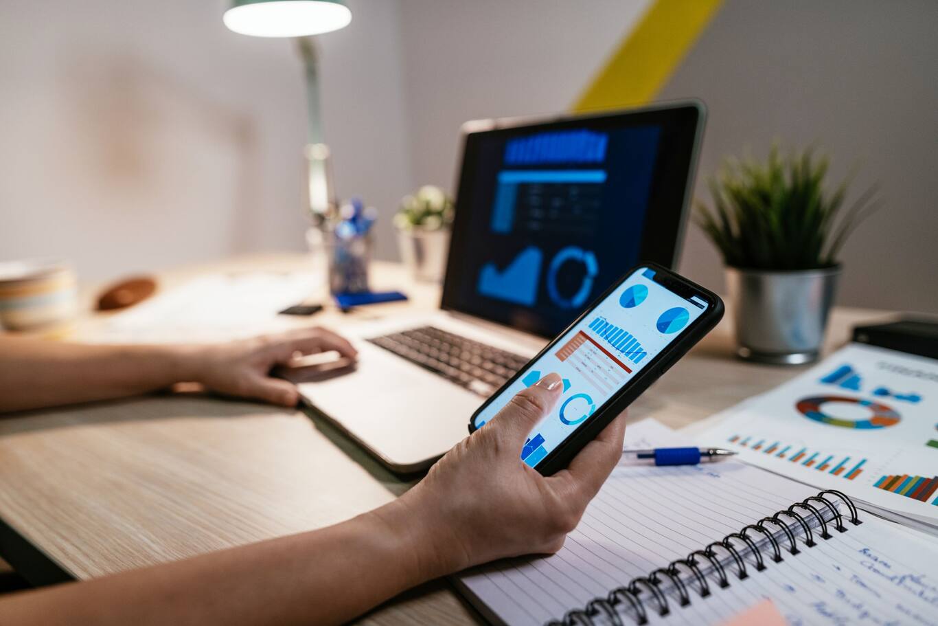 Ženská ruka, ktorá drží mobil a kontroluje si výpisy z dôchodkových účtov