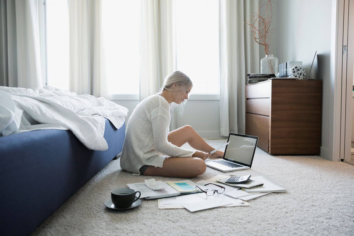 Žena sediaca na zemi za počítačom, ktorá porovnáva dôchodkové piliere