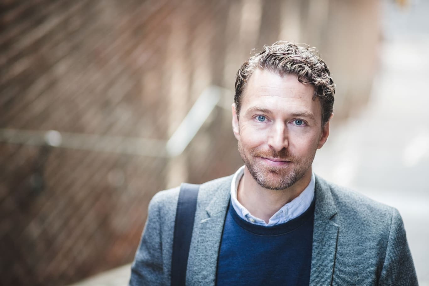 Sebavedomý podnikateľ s modrými očami na ulici s rozmazaným pozadím