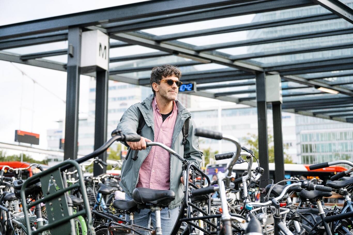 Muž v slnečných okuliaroch na ceste z práce na parkovisku bicyklov