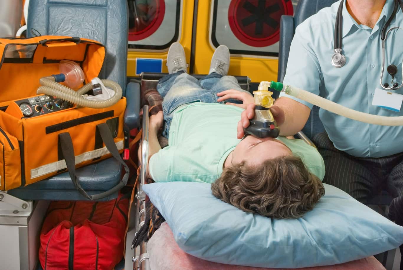 Pacient leží na nosítkách v sanitce během převozu po úrazu. Závažné úrazy mohou vést k dlouhé léčbě, výpadku příjmu a trvalým následkům, na které se zaměřuje životní i úrazové pojištění.